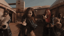 a group of women are dancing in front of a building with the letter s on the bottom