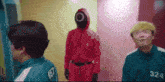 a man in a red suit with a mask on his head is standing next to another man in a green jacket with the number 324 on it