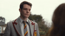 a young man in a suit and tie is looking at a woman