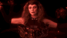 scarlet witch is a superhero with red eyes and red hair in a dark room .