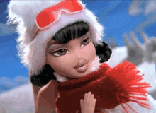 a doll wearing a hat and scarf is waving her hand