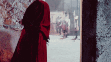 a woman in a red dress is standing in a doorway looking out