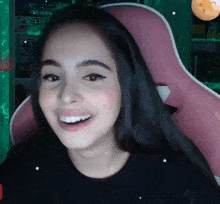 a girl with long black hair is smiling and wearing a black shirt