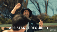 a man in a cowboy hat stands in front of the words assistance required