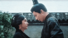 a man and a woman are looking at each other in front of a building .