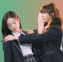 two girls in school uniforms are standing next to each other and one is putting her hand on the other 's shoulder