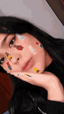 a girl with teddy bears on her face is taking a selfie .