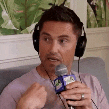a man is wearing headphones and holding a microphone with a cube on it that says ' miami ' on it