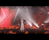 a woman in a white dress is standing on a stage in front of a red heart