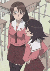 two girls are standing next to each other in a classroom