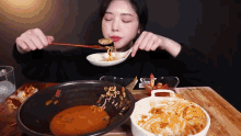 a woman is eating a bowl of food with a spoon and fork .