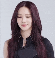 a close up of a woman with long red hair wearing a black top and earrings .