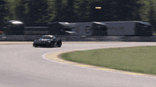 a race car is going around a curve on a track with a truck in the background that has the word eme on it