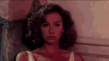 a woman in a white dress is leaning against a wall in a room .
