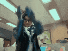 a woman wearing headphones and a blue jacket is dancing in an office cubicle