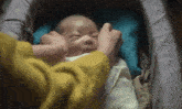 a woman in a yellow sweater is putting a baby in a crib