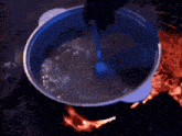 a blue pot filled with water is sitting next to a burning fire