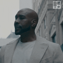 a man in a suit stands in front of a sign that says be
