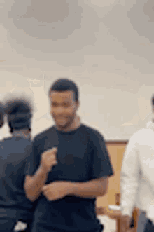 a man in a black shirt is talking to another man in a room .