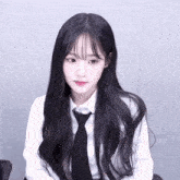 a girl with long black hair wears a white shirt and black tie
