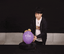 a man is blowing up a purple balloon in front of a digital clock that says 59
