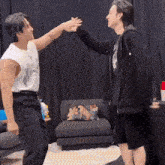 two men are giving each other a high five in front of a couch