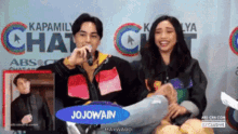a man and woman are sitting in front of a sign that says kapamilya chat