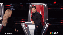 a man and a woman are hugging in a red chair with nbc written on the bottom