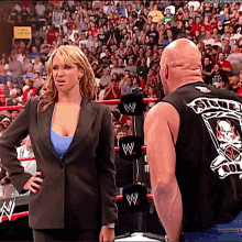 a man and a woman are standing in a wrestling ring and the man is wearing a black vest with a skull on it