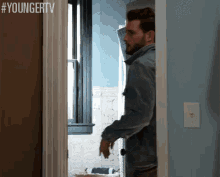 a man with a beard is standing in a doorway .