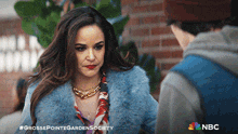 a woman in a blue fur coat is talking to a man in a nbc advertisement