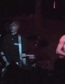 a man in a black shirt is playing a guitar in a dark room .