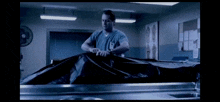 a man in a surgical scrub is holding a black bag over a body