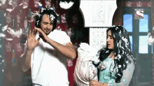a man and a woman are covered in feathers and a sony television advertisement can be seen behind them