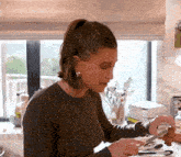a woman in a black sweater is cutting a piece of meat