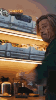 a man is standing in front of a shelf that says thursday