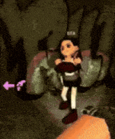 a video game character is being held by a person in a cave .