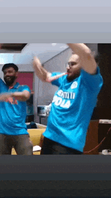 two men in blue shirts are dancing in a room .
