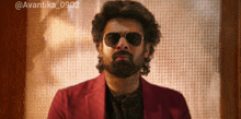 a man with a beard wearing sunglasses and a red jacket with the hashtag @avantika_0902