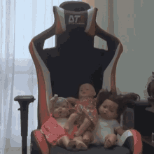 three dolls are sitting in a chair with their heads on the back of the chair .