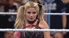 a woman with pigtails is standing in a wrestling ring and looking at the camera .