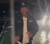 a man wearing a supreme jacket and a ny yankees hat