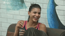 a woman is sitting on a couch with a playplus logo on the bottom right