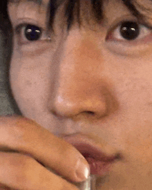 a close up of a person 's face with a glass in their hand .