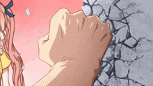 a person 's fist is against a concrete wall