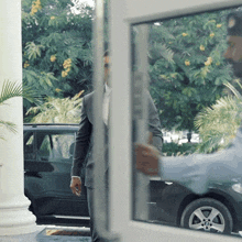 a man in a suit is walking towards a car