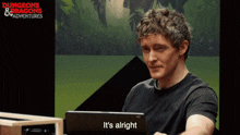 a man sitting in front of a laptop that says it 's alright on it
