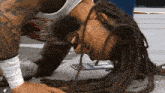 a wrestler with dreadlocks is laying on the ground with his head down