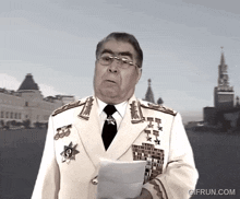 a man in a military uniform is holding a piece of paper with a gifrun.com watermark