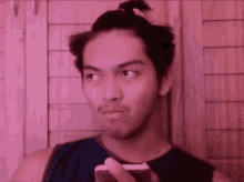 a man with a ponytail is holding a cell phone and making a funny face